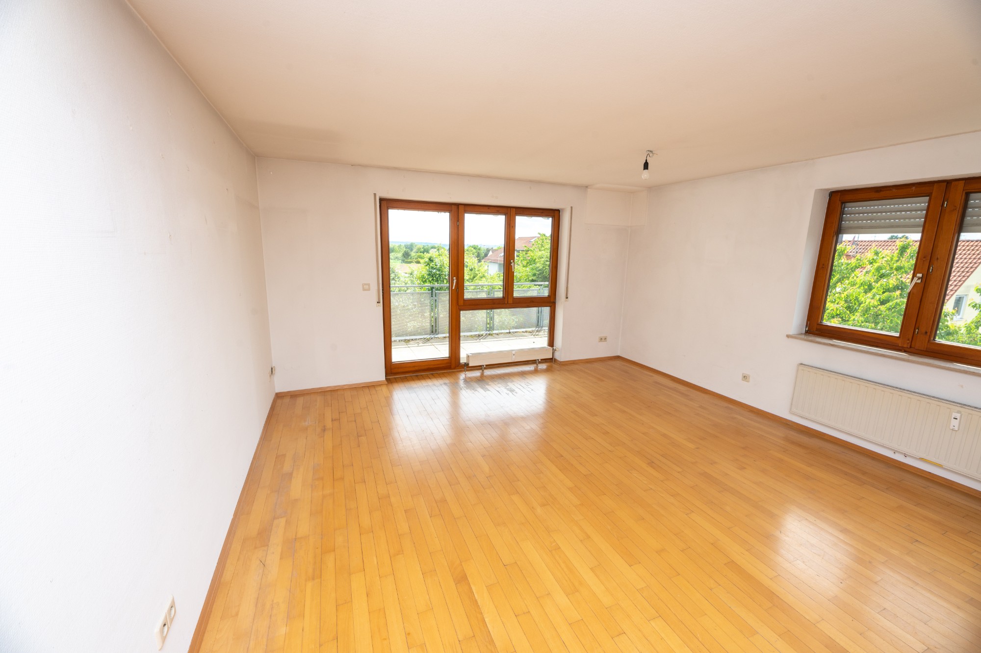 Dasselbe Wohnzimmer nach der Räumung: leer mit Parkettboden