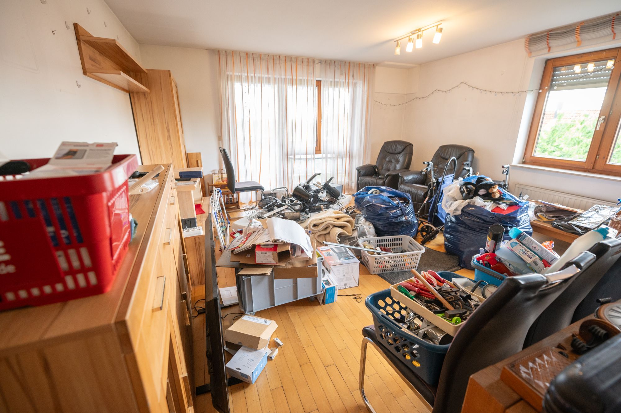 Wohnzimmer vor der Räumung: voller Hausrat, Säcke, Körbe und Möbel